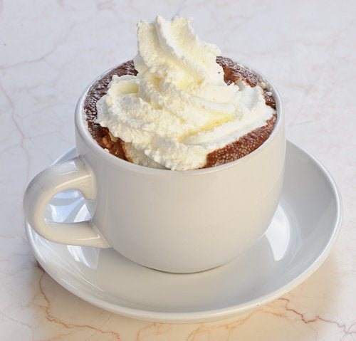 A white mug on a saucer filled with dark hot chocolate and a dollop of whipped cream