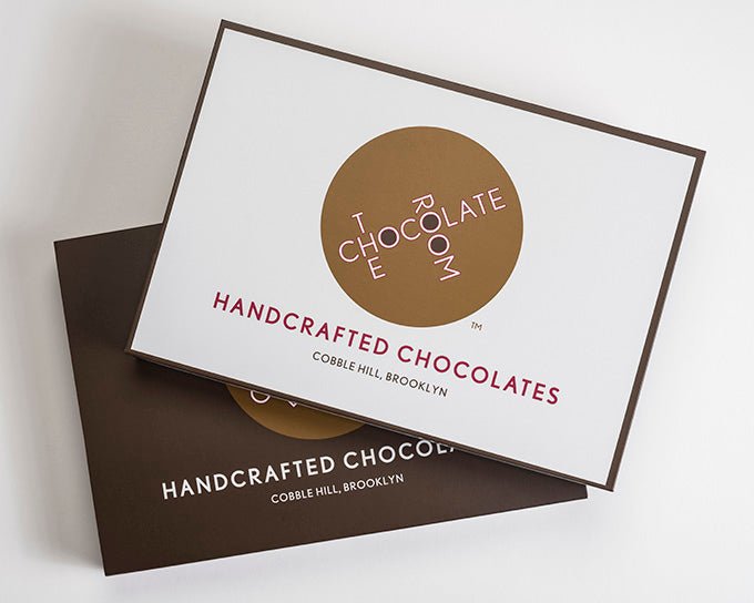 
                  
                    Stack of 2 12 piece bonbon boxes. One shows the box without the sleeve revealing a white box frame in brown with our logo
                  
                